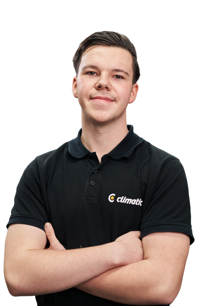 Ein junger, lächelnder Mann mit kurzen dunklen Haaren, der ein schwarzes Poloshirt mit dem weißen Logo-Schriftzug „climatic“ auf der linken Brustseite trägt und die Arme vor dem Körper verschränkt hat.